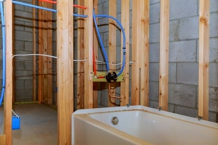 Bathroom remodel showing under floor plumbing work connecting installation of pipes for water for new buildings